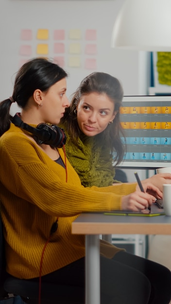 Free Photo confident women photo editors sitting at workplace in creative studio