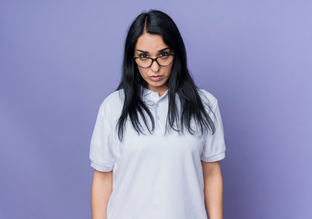 Confident young brunette caucasian girl in optical glasses looks isolated on purple wall