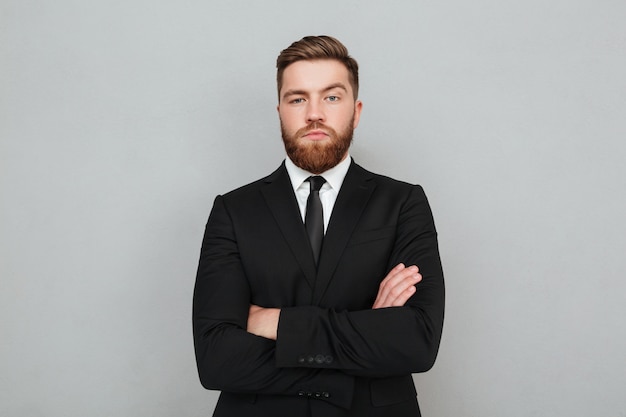 Free photo confident young businessman in suit standing with arms folded