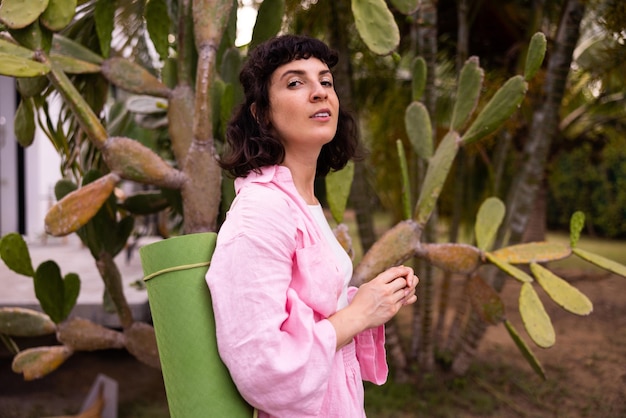 Free Photo confident young caucasian brunette girl in pink shirt looks at camera on background of cactus lifestyle concept