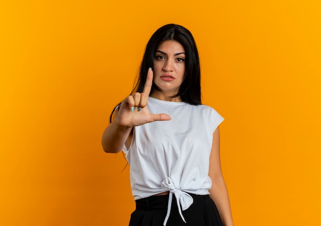 Confident young caucasian woman gestures gun hand sign pointing up