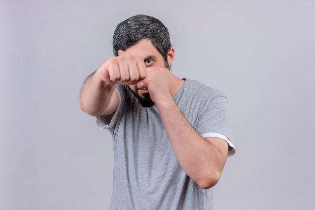 Confident young handsome caucasian man doing boxing gesture isolated on white  with copy space