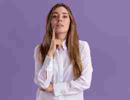 Free photo confident young pretty caucasian girl puts finger on chin and looks at camera on purple