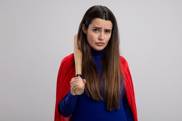 Confident young superhero girl putting baseball bat on shoulder isolated on white