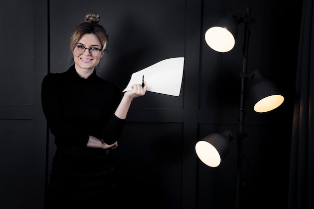 Confident young woman holding papers at the office