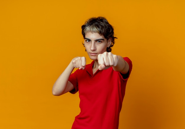 confident young woman with pixie haircut doing boxing gesture at front