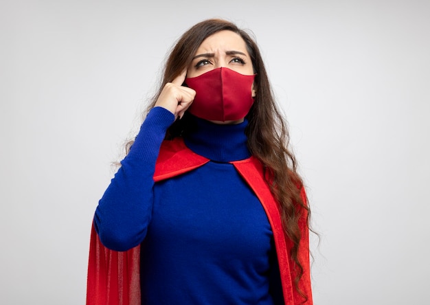 Confused caucasian superhero girl with red cape wearing red protective mask