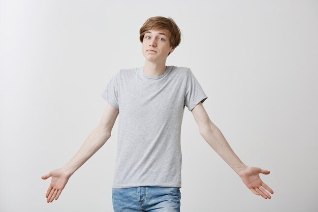 Free Photo confused fair-haired male with blue eyes, curving lips, dressed casually, standing  shrugging shoulders having doubtful look not knowing what to choose. body language concept