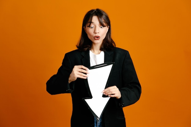 Free Photo confused holding direction mark young beautiful female wearing black jacket isolated on orange background