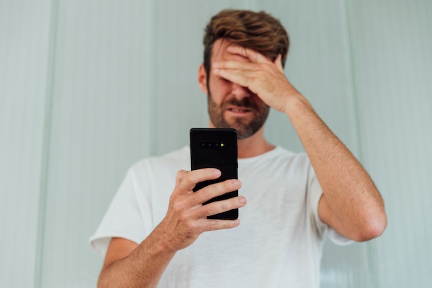 Confused man holding modern phone