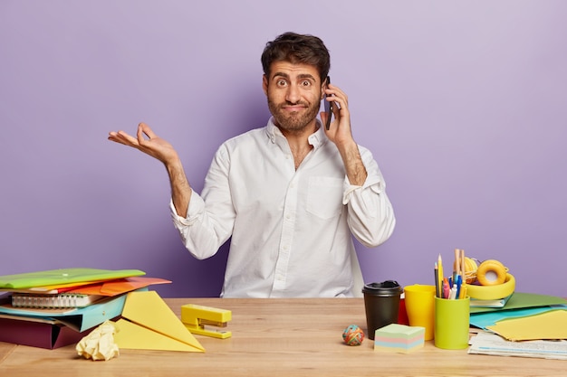 Confused puzzled employee sitting at the office desk