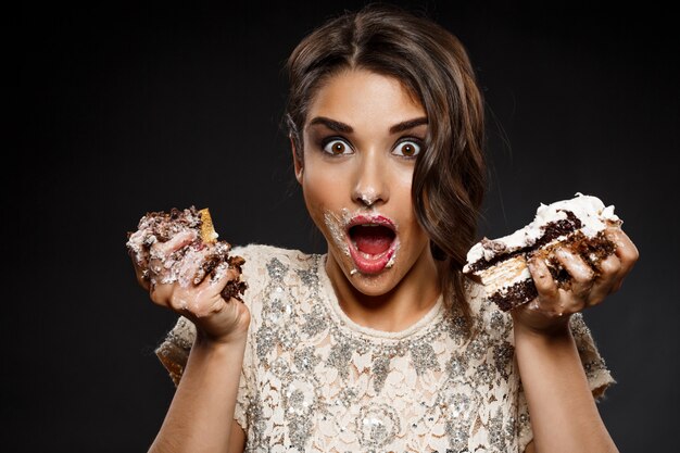 Confused woman in creamy dress holding piece of cake