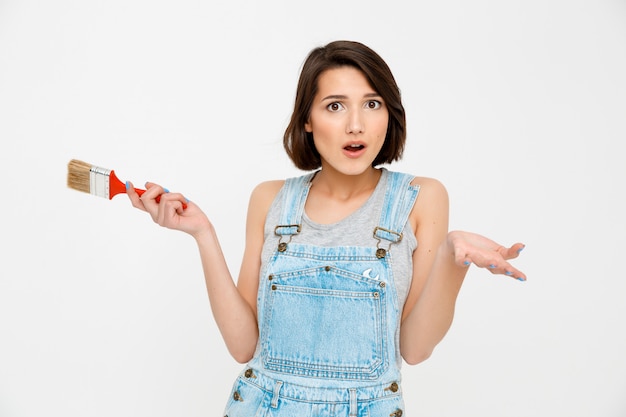 Confused woman hold painting brush and shrug clueless