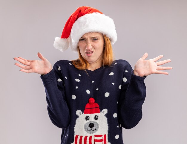 Confused young beautiful girl wearing christmas hat spreading hands isolated on white background