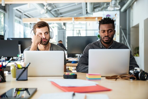 Confused young colleagues sitting in office coworking