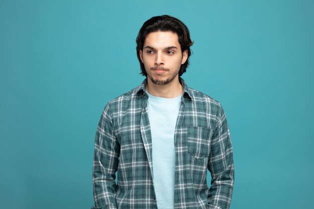 confused young handsome man looking at side isolated on blue background