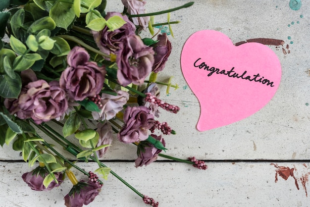 Free Photo congratulation note in heart shape paper with purple bouque