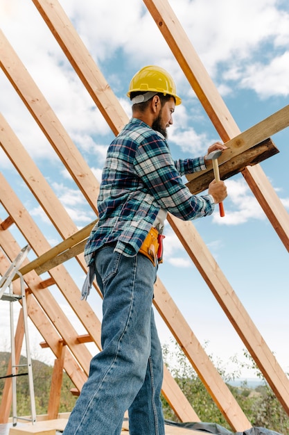 Free photo construction worker with hard hat building the roof of the house