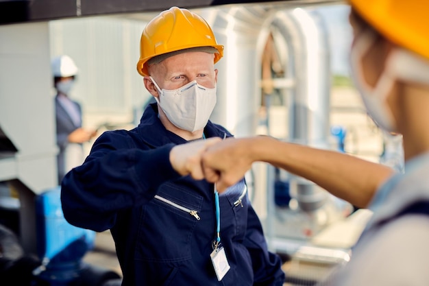 Construction workers with face masks fist bumping during coronavirus epidemic