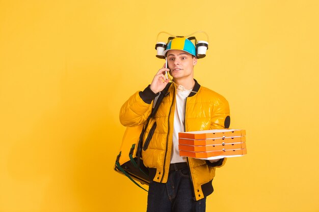 Contacless delivery service during quarantine. Man delivers food and shopping bags during insulation. Emotions of deliveryman isolated on yellow