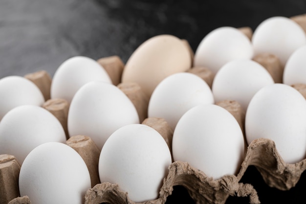 Container of white eggs on black surface. 