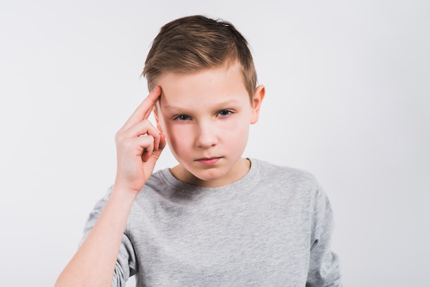 Contemplated boy looking to camera standing against grey background