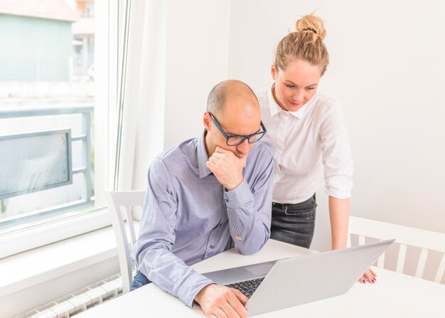 Contemplated businessman and businesswoman looking at laptop