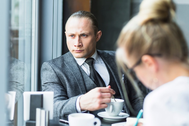 Free photo contemplated businessman with cup of tea sitting in restaurant