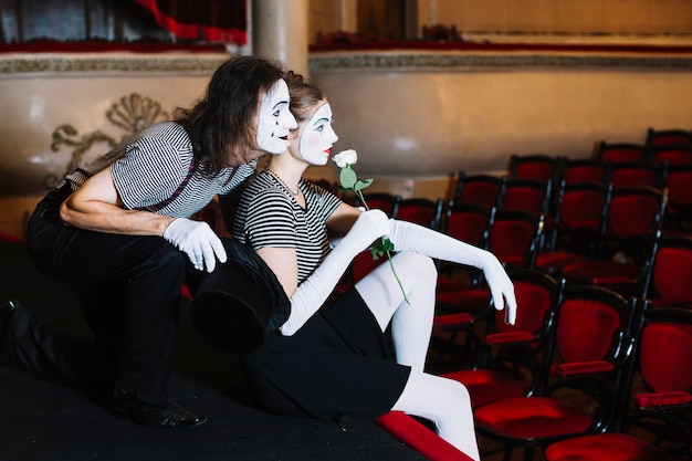 Free Photo contemplated couple mime artist sitting on stage in the auditorium