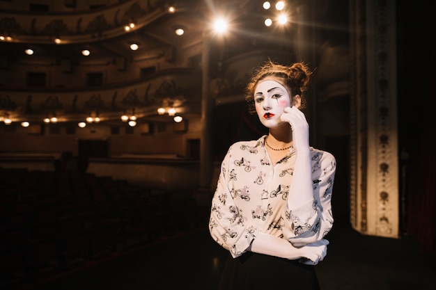 Free photo contemplated female mime standing on stage in auditorium