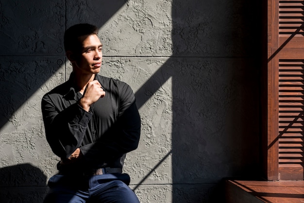 Contemplated young man sitting in front of wall