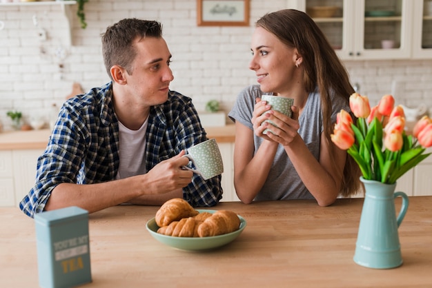 Free photo content couple sitting at table and enjoying tea