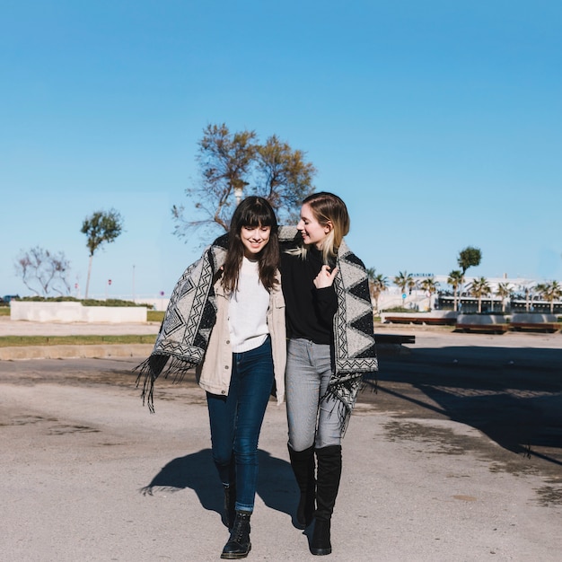 Content girlfriends in scarf walking together