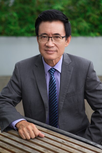 Content Senior Businessman Sitting at Cafe Table