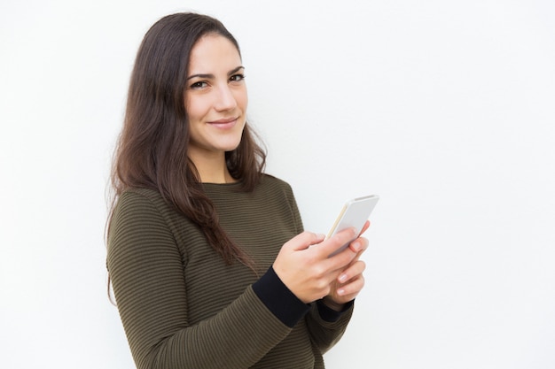 Content smiling Latin woman holding cellphone