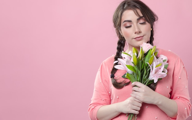 Free photo content woman posing while holding bouquet of lilies in hands