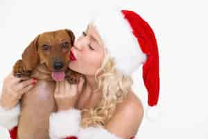 Free photo content woman in santa hat kissing cute dog