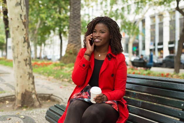 Content woman sitting on bench and talking by phone