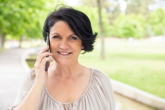 Content woman talking by smartphone outdoors