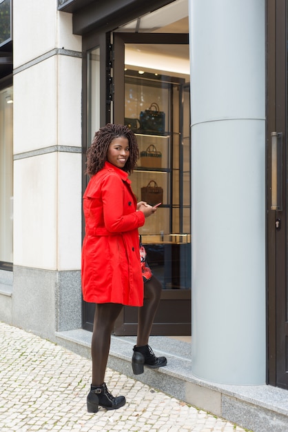 Content woman with smartphone entering shop