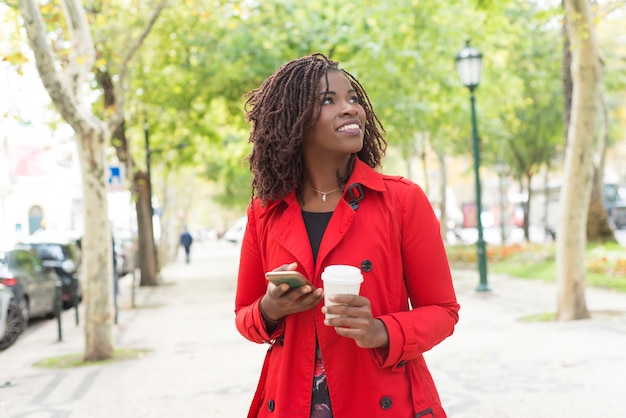 Content woman with smartphone and paper cup