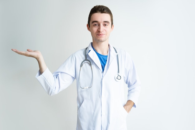 Content young male doctor holding empty space on palm