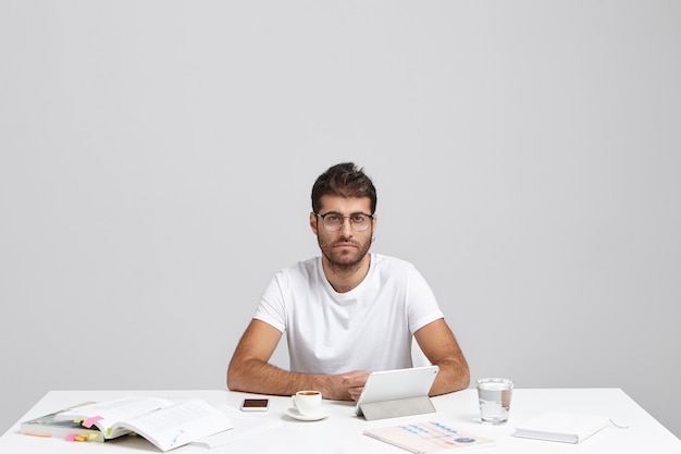 Convinced Caucasian man with stubble and trendy hairstyle, wears casual t shirt