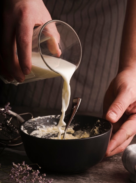 Cook adding milk to bowl mixture