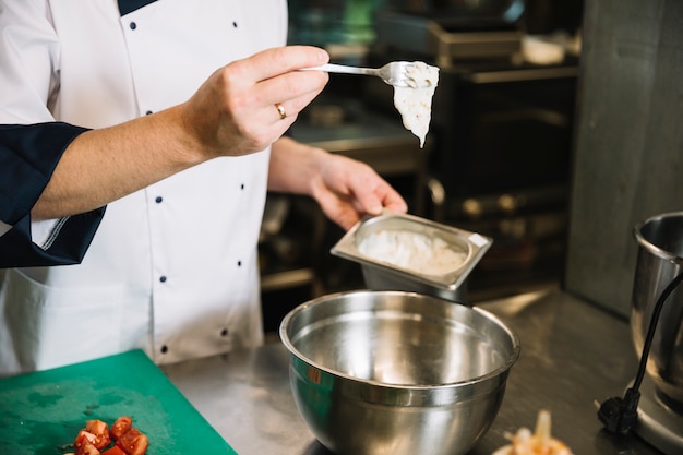 Free photo cook adding sauce from container in bowl