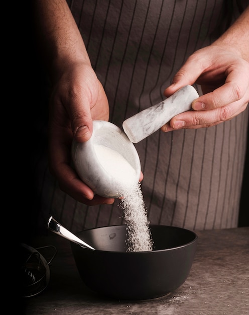 Cook adding sugar from mortar into bowl