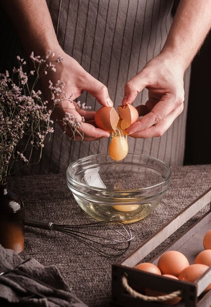 Cook breaking eggs in bowl