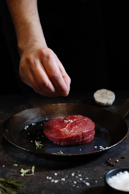 Free photo cook cooking fresh peace of meat on board dark background cooking concept