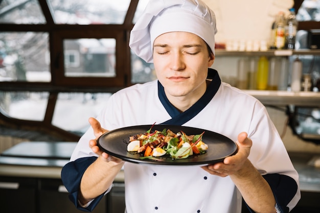 Free Photo cook smelling salad with meat on plate