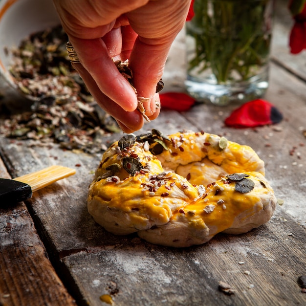 Cook sprinkling spice with hand onto twisted pastry close-up.